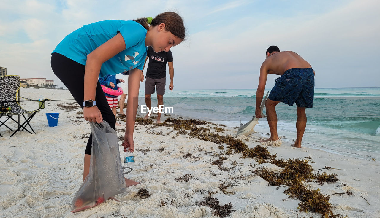 beach, land, sea, water, sand, vacation, adult, nature, men, sky, ocean, holiday, two people, leisure activity, full length, trip, women, lifestyles, togetherness, sports, coast, body of water, day, young adult, friendship, bending, standing, travel, female, outdoors, clothing, casual clothing, child, summer, childhood, motion, swimming, fun, bonding