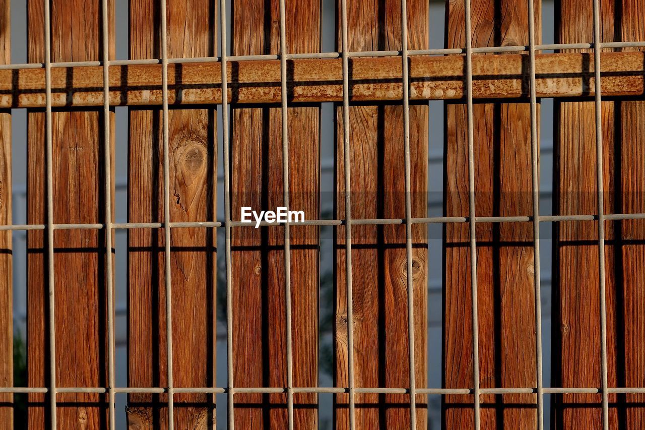 FULL FRAME SHOT OF METAL FENCE AGAINST BUILDING