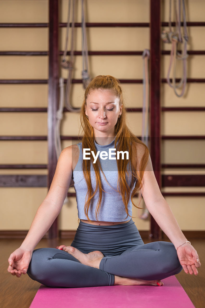 A woman sits in a meditative lotus position, eyes closed, with a sense of inner peace