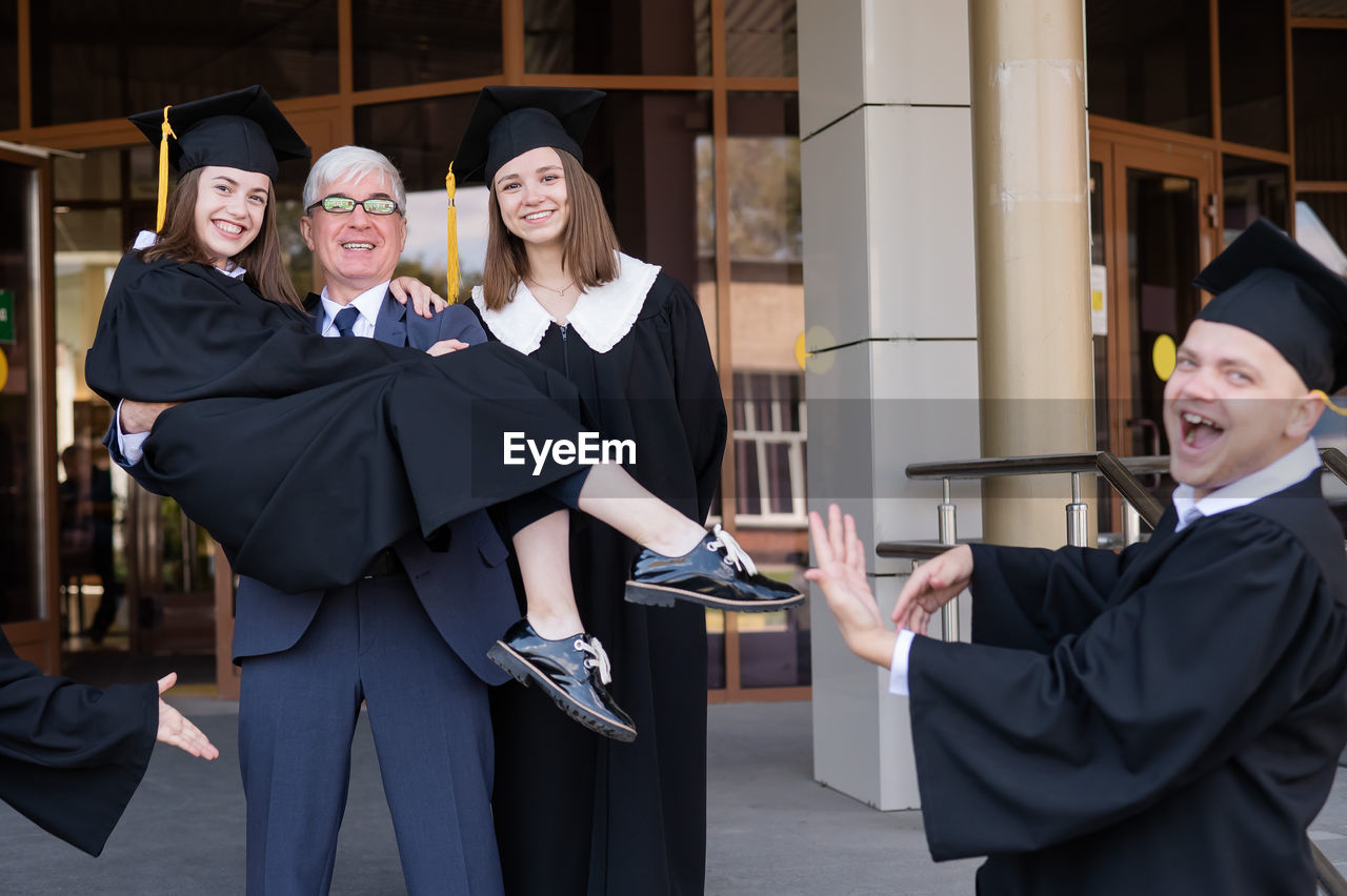 portrait of woman wearing graduation gown standing in city