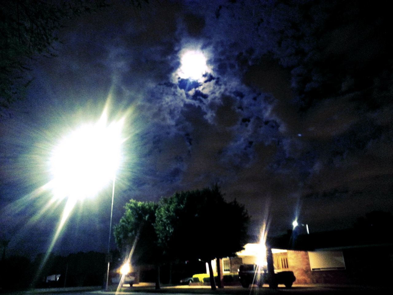 LOW ANGLE VIEW OF ILLUMINATED STREET LIGHTS AGAINST SKY