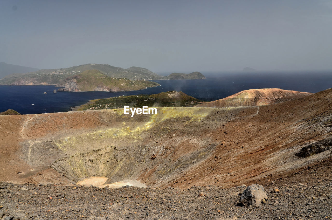 Barren landscape against calm blue sea