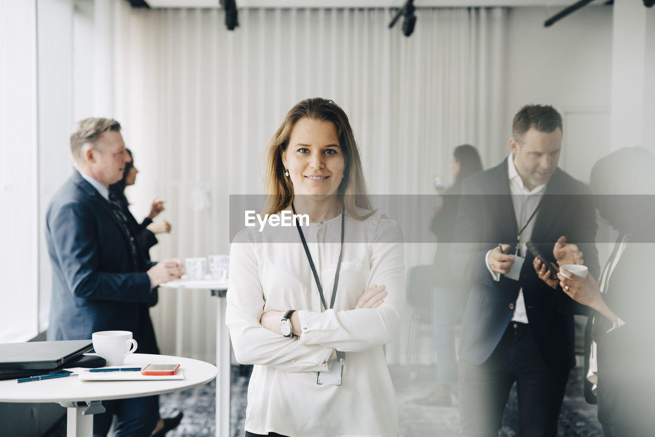 Portrait of confident businesswoman with arms crossed standing at workplace