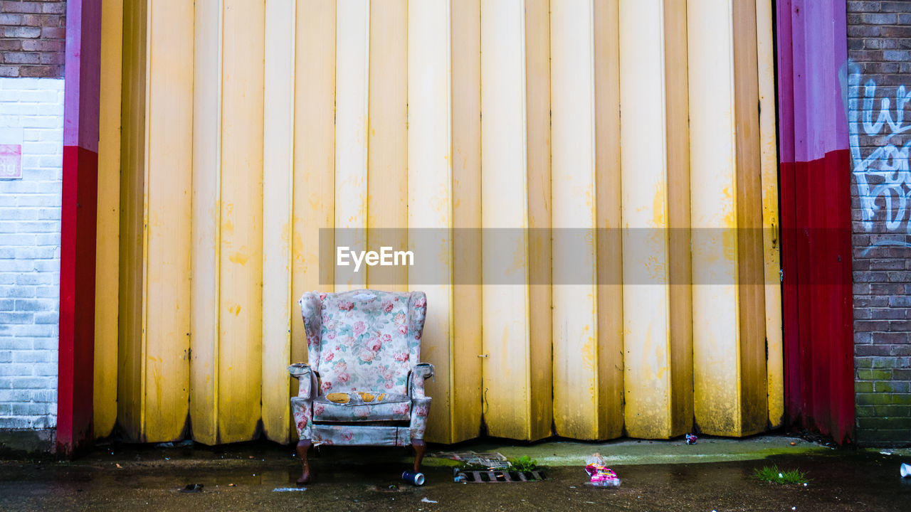 Abandoned armchair against wall