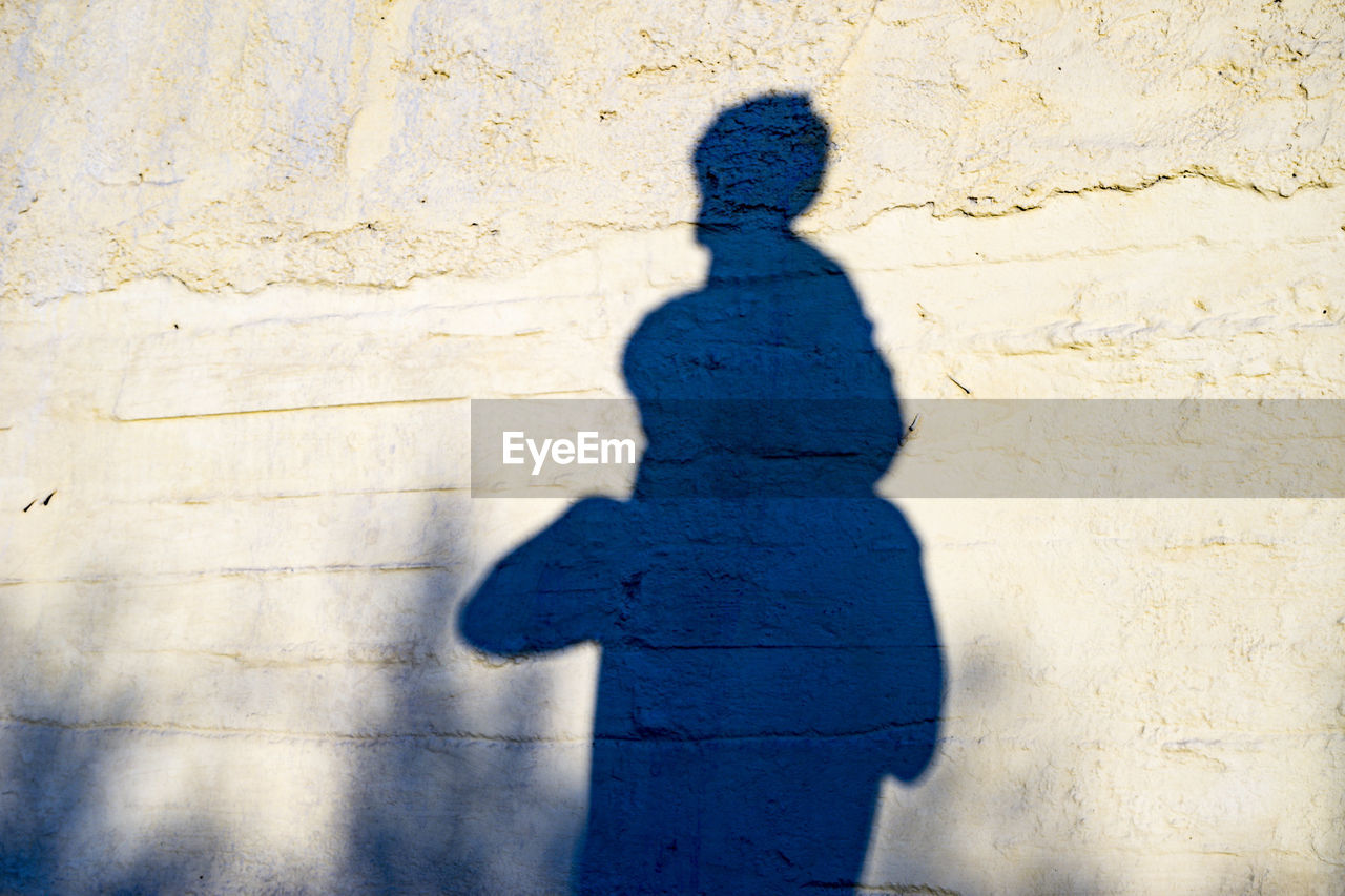 SHADOW OF MAN ON TILED WALL