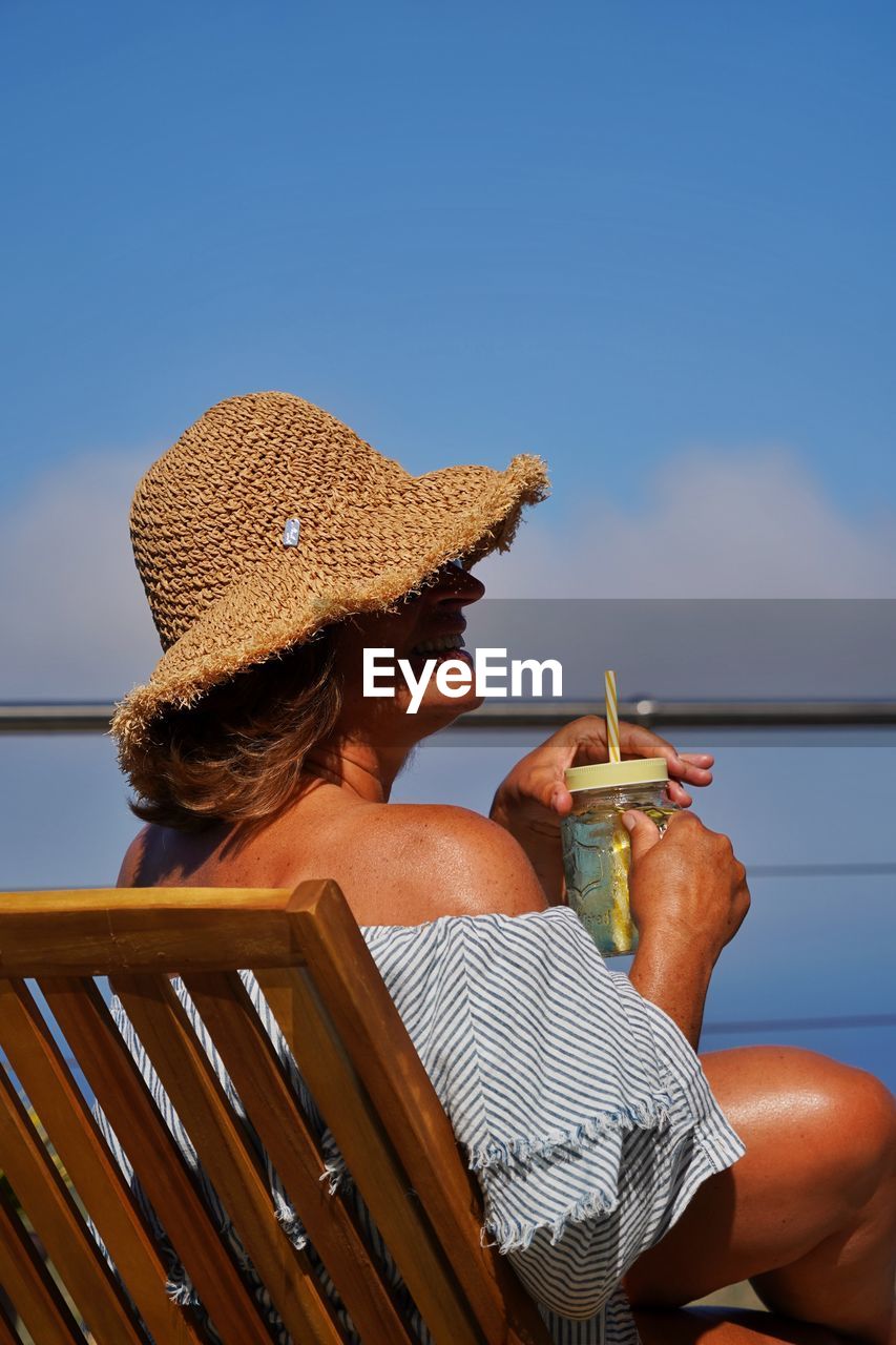 Rear view of woman sitting at beach against clear sky