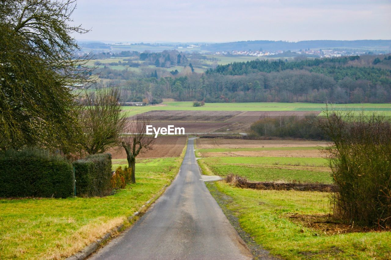 Road amidst field against sky