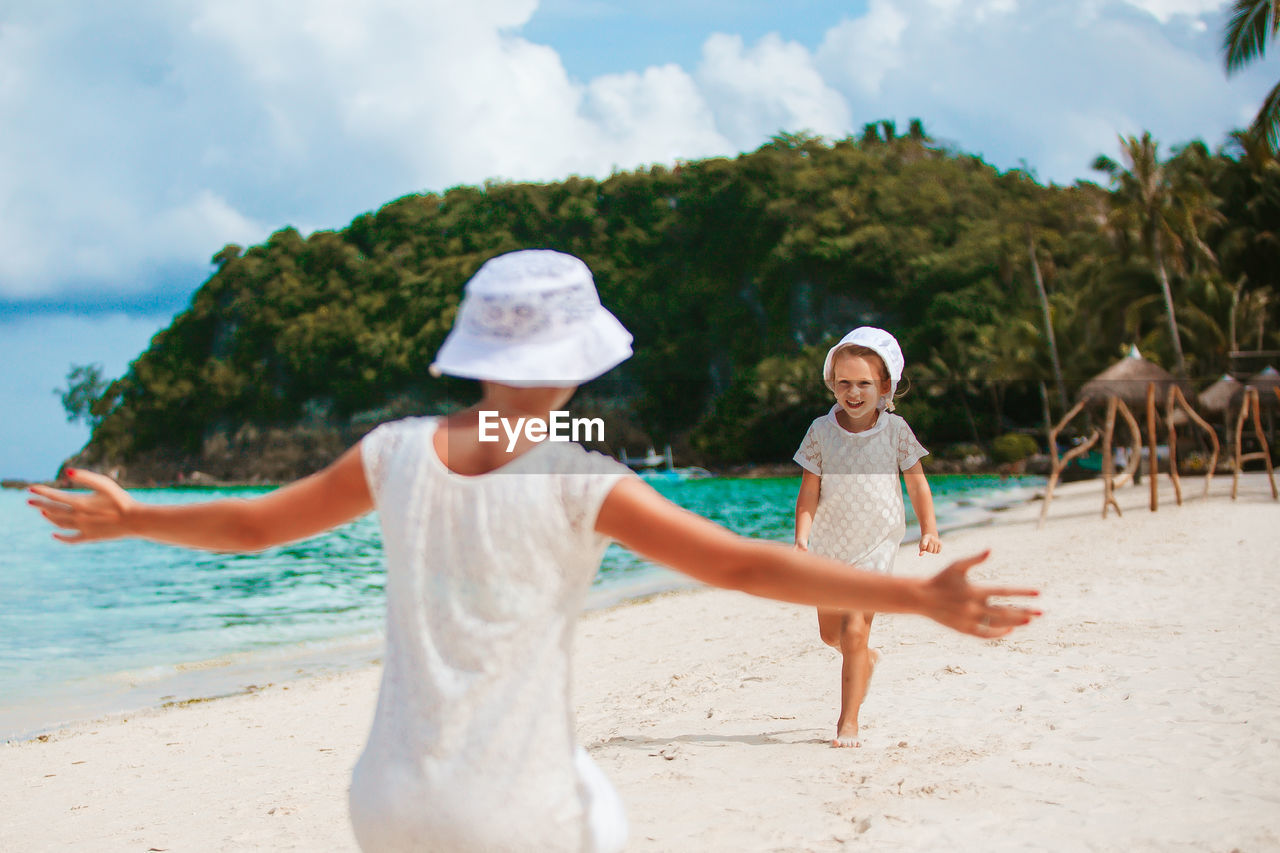 Rear view of girl with arms outstretched standing on beach