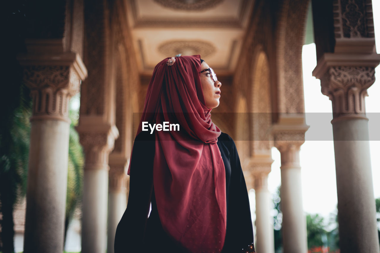 Low angle view of young woman wearing hijab standing in temple