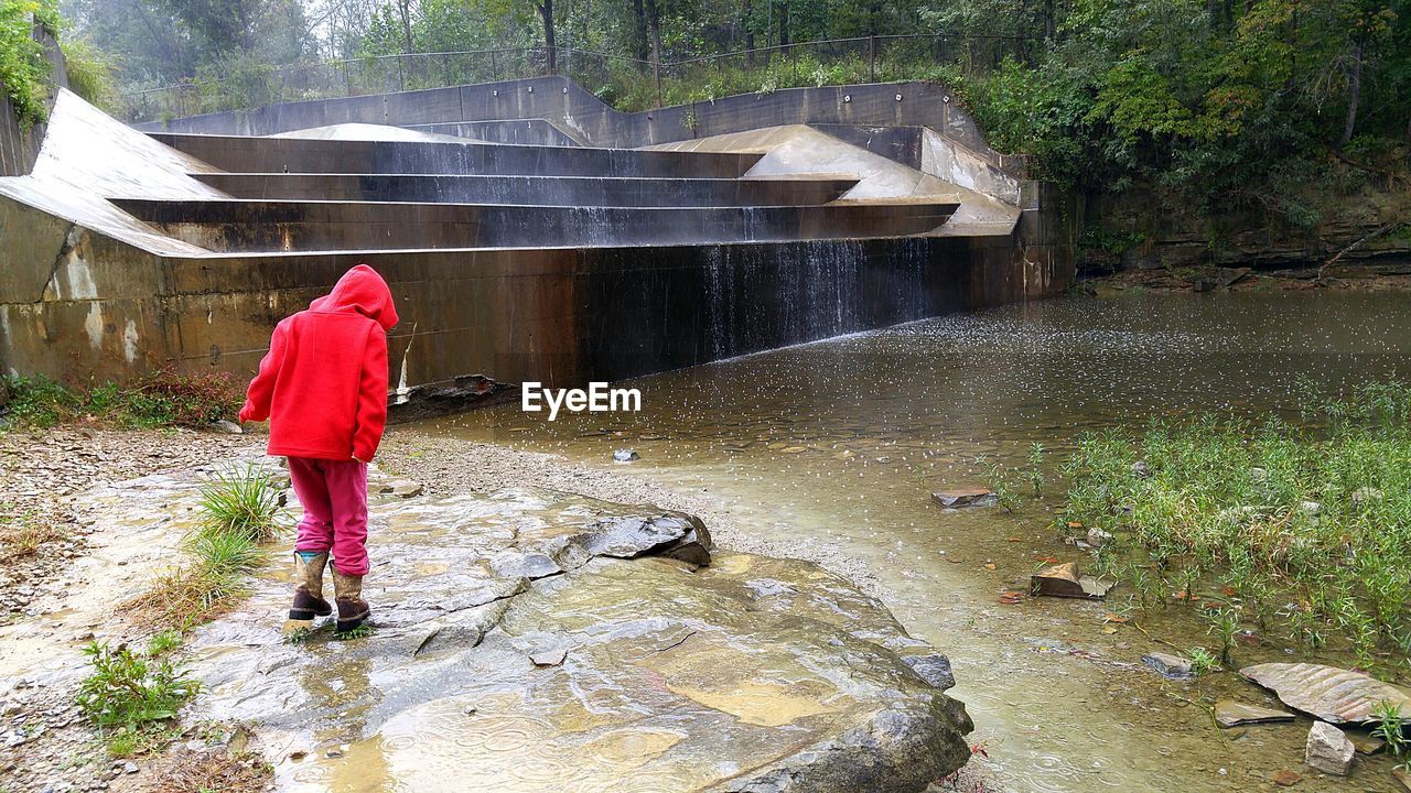 Rear view of girl standing by lake at park