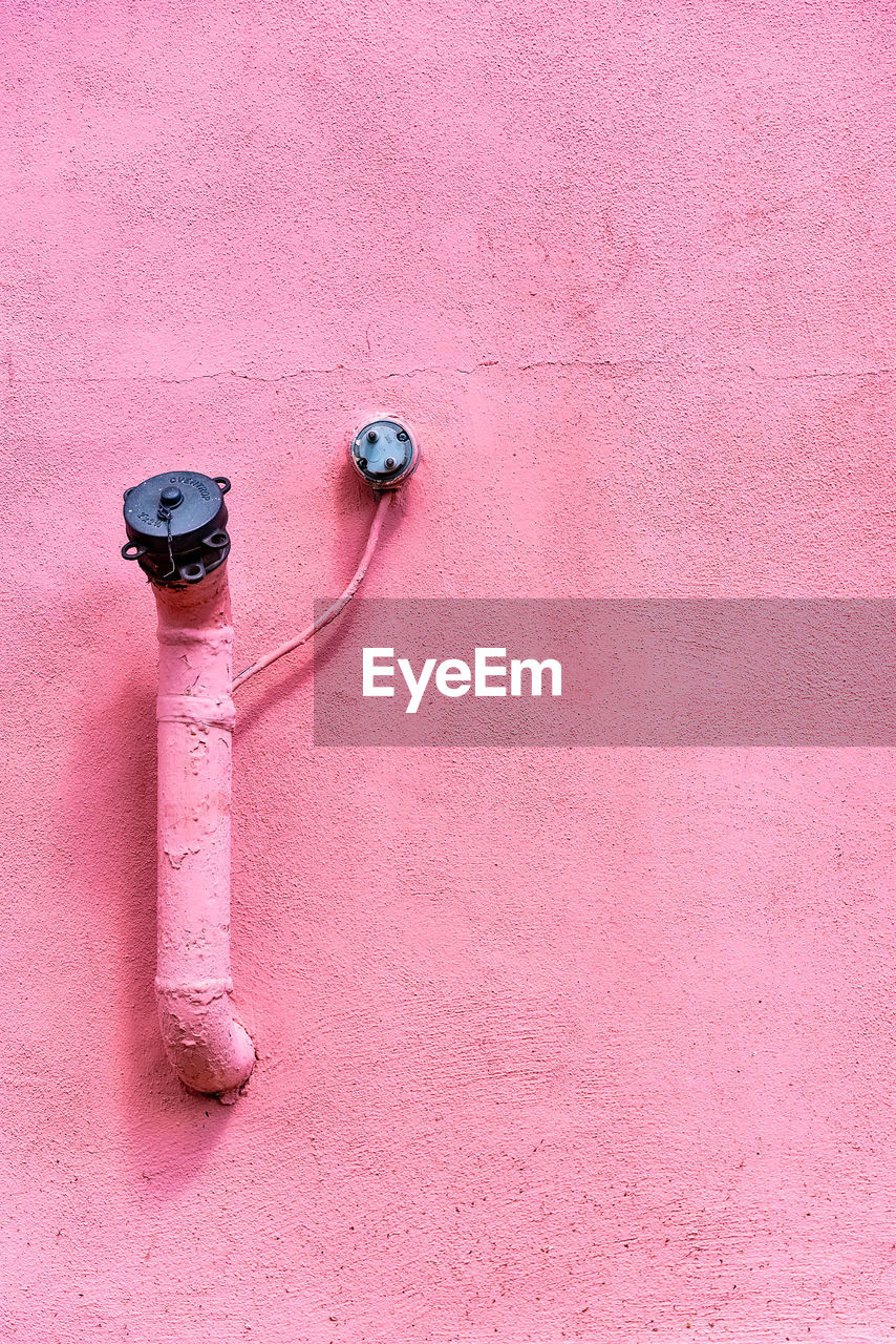 Close-up of pipes on pink painted wall