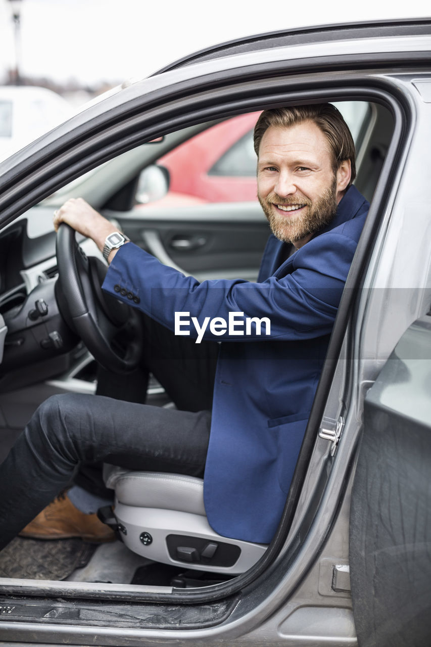 Side view portrait of mid adult businessman sitting in car