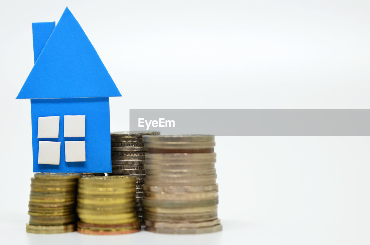 Stacked coins with model house over white background