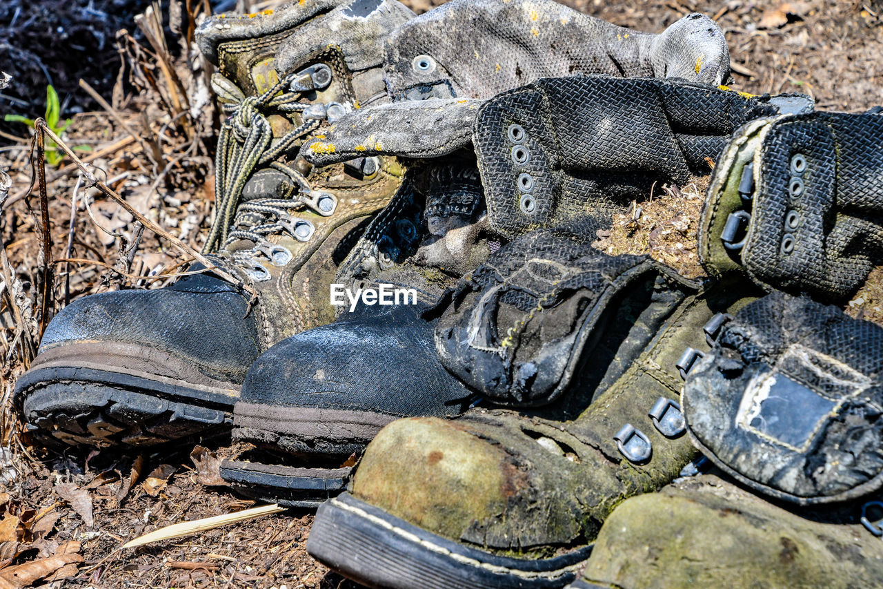 Close-up of old boots and gloves on land