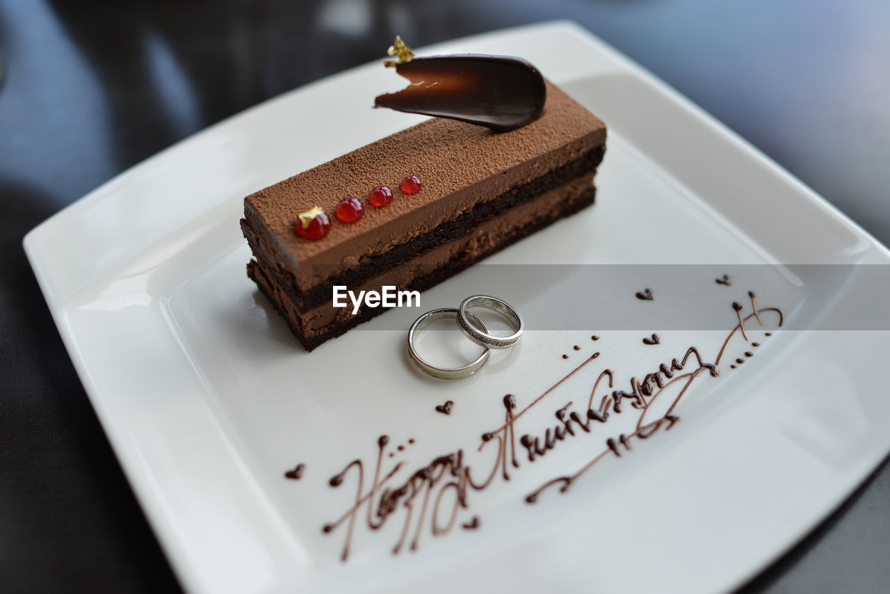 High angle view of rings and cakes on plate during wedding anniversary