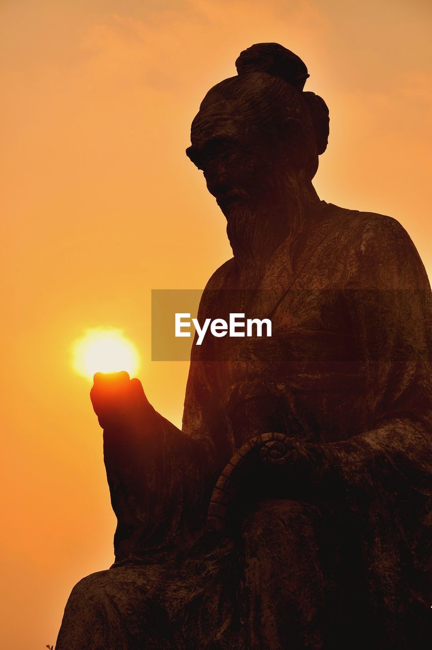 Old statue against clear sky during sunset