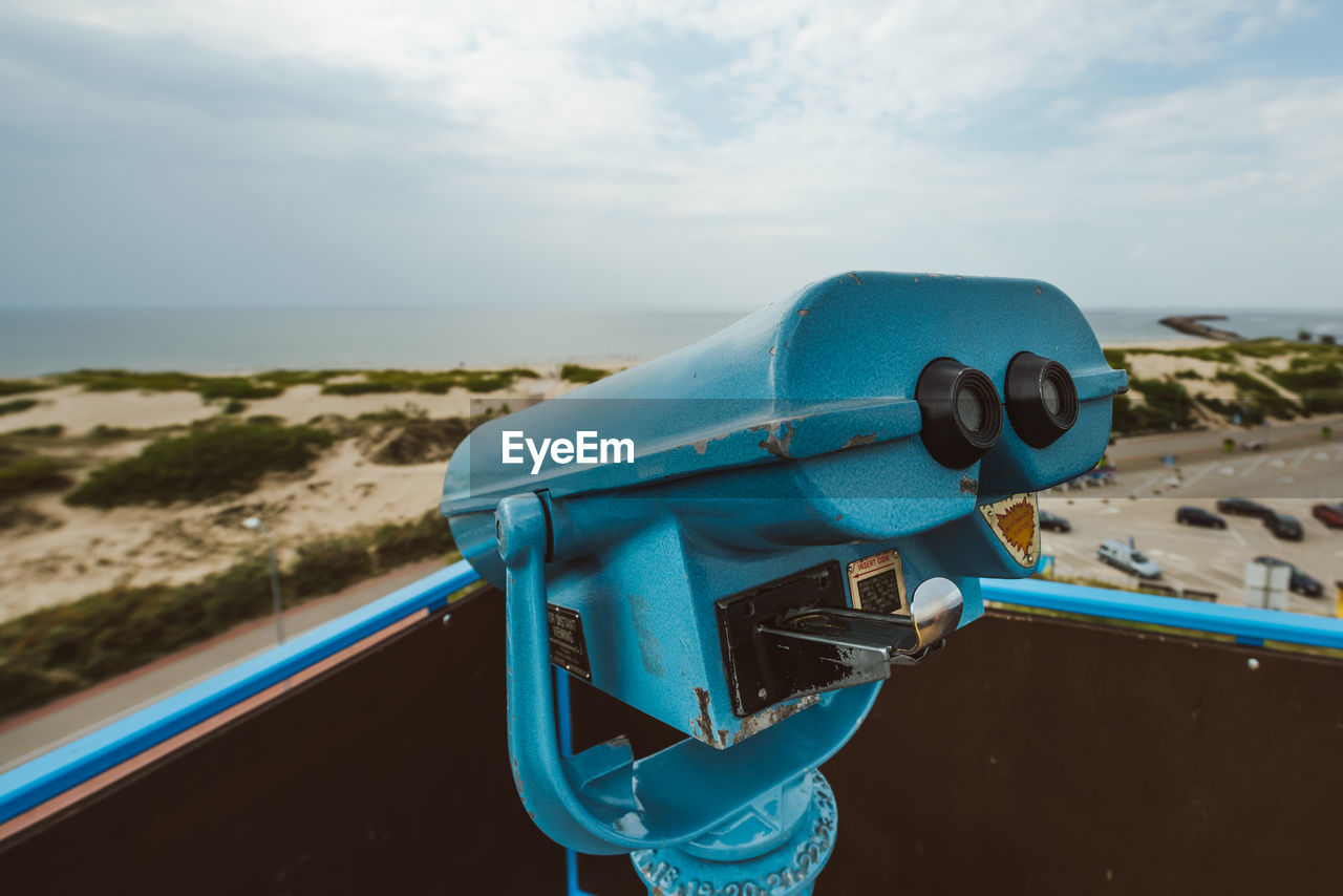 Close-up of coin-operated binoculars against sea