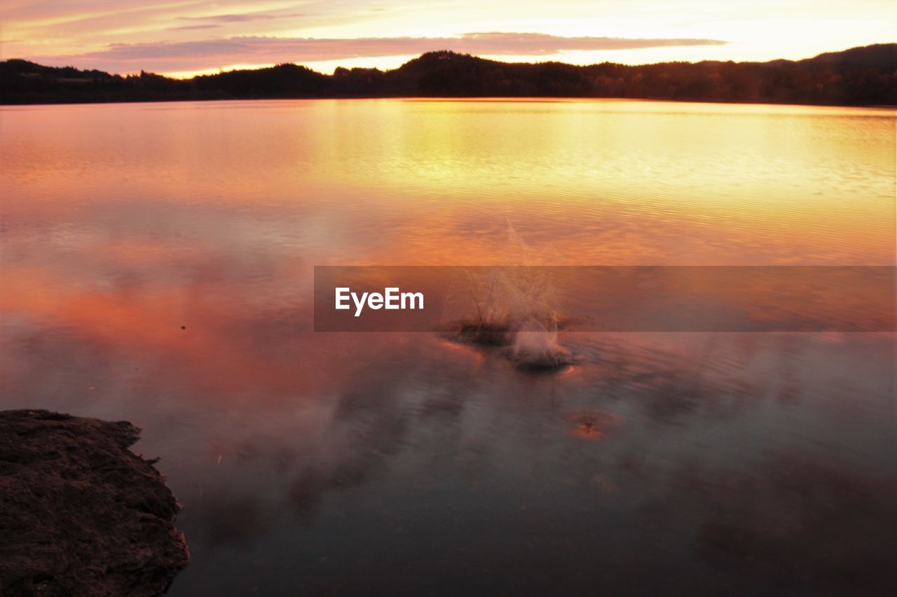 Scenic shot of calm countryside lake at sunset