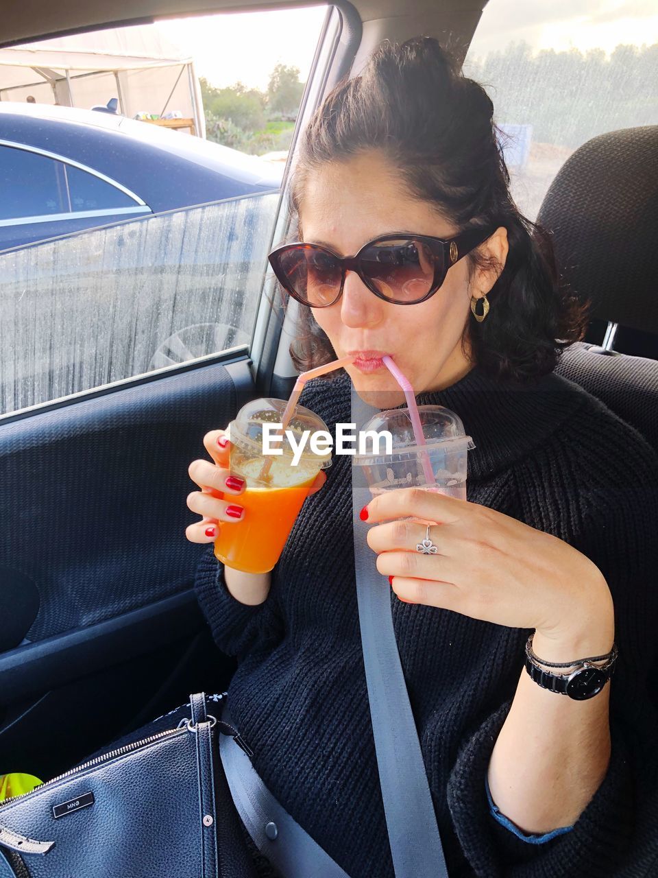Woman having drinks while traveling in car