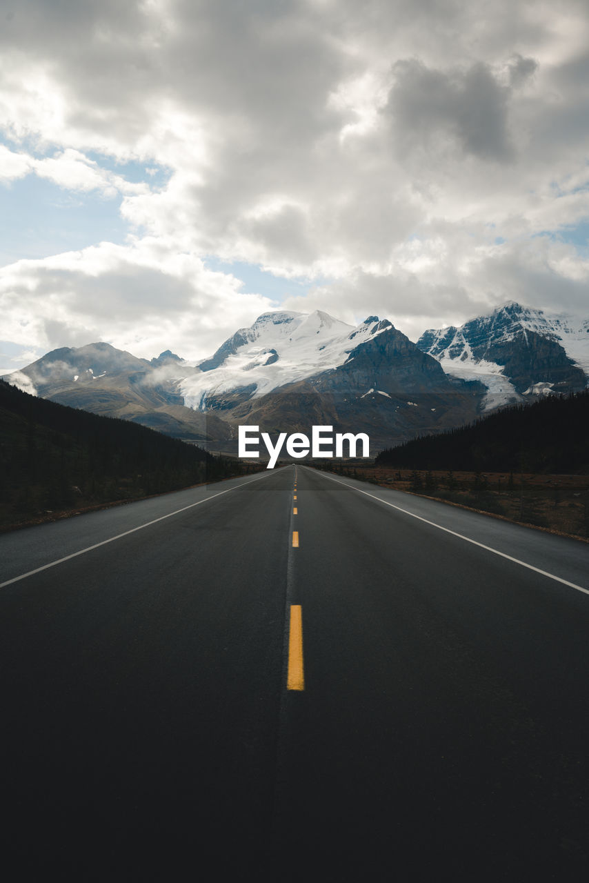 Road leading towards snowcapped mountains against sky