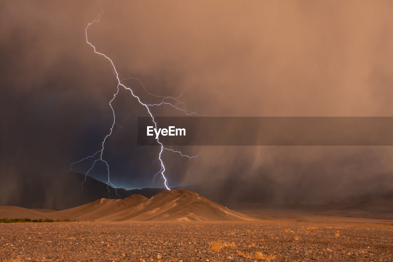 View of lightning over mountains during storm during sunset
