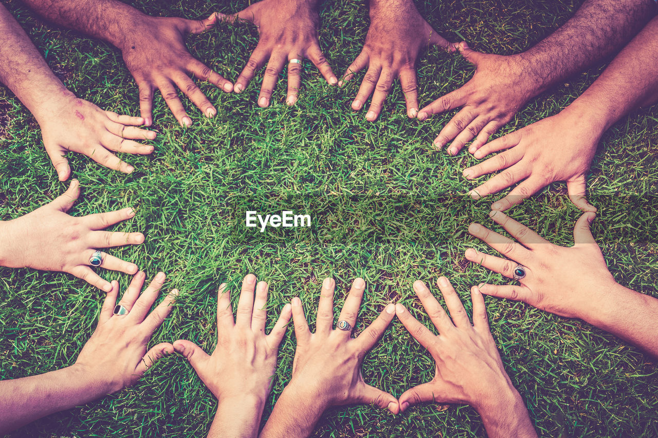 Cropped hands of friends on grass