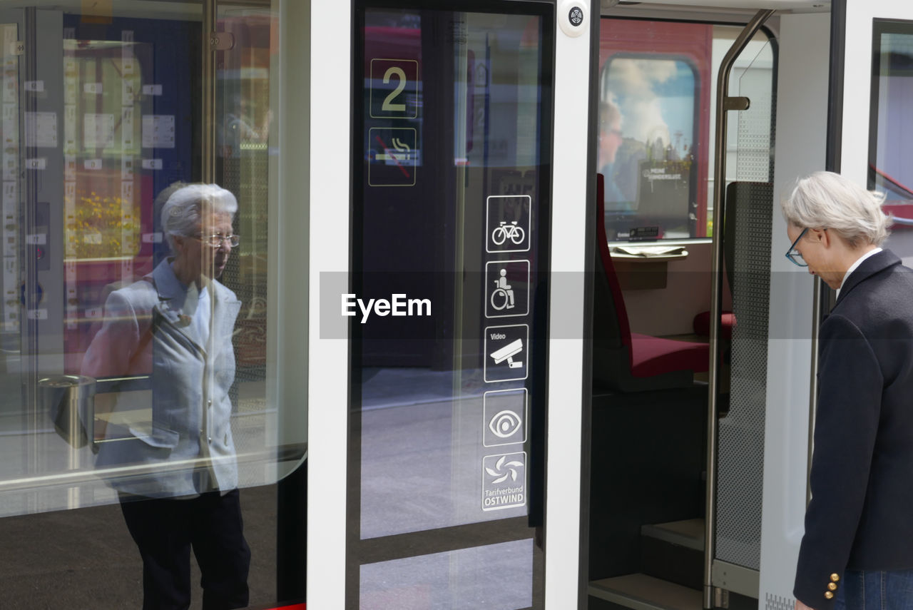 REFLECTION OF PEOPLE ON GLASS WINDOW OF BUS