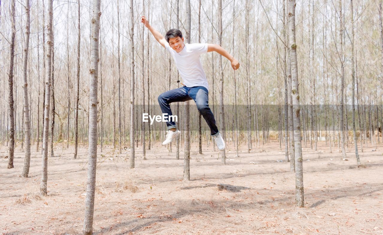 Full length portrait of man jumping in forest