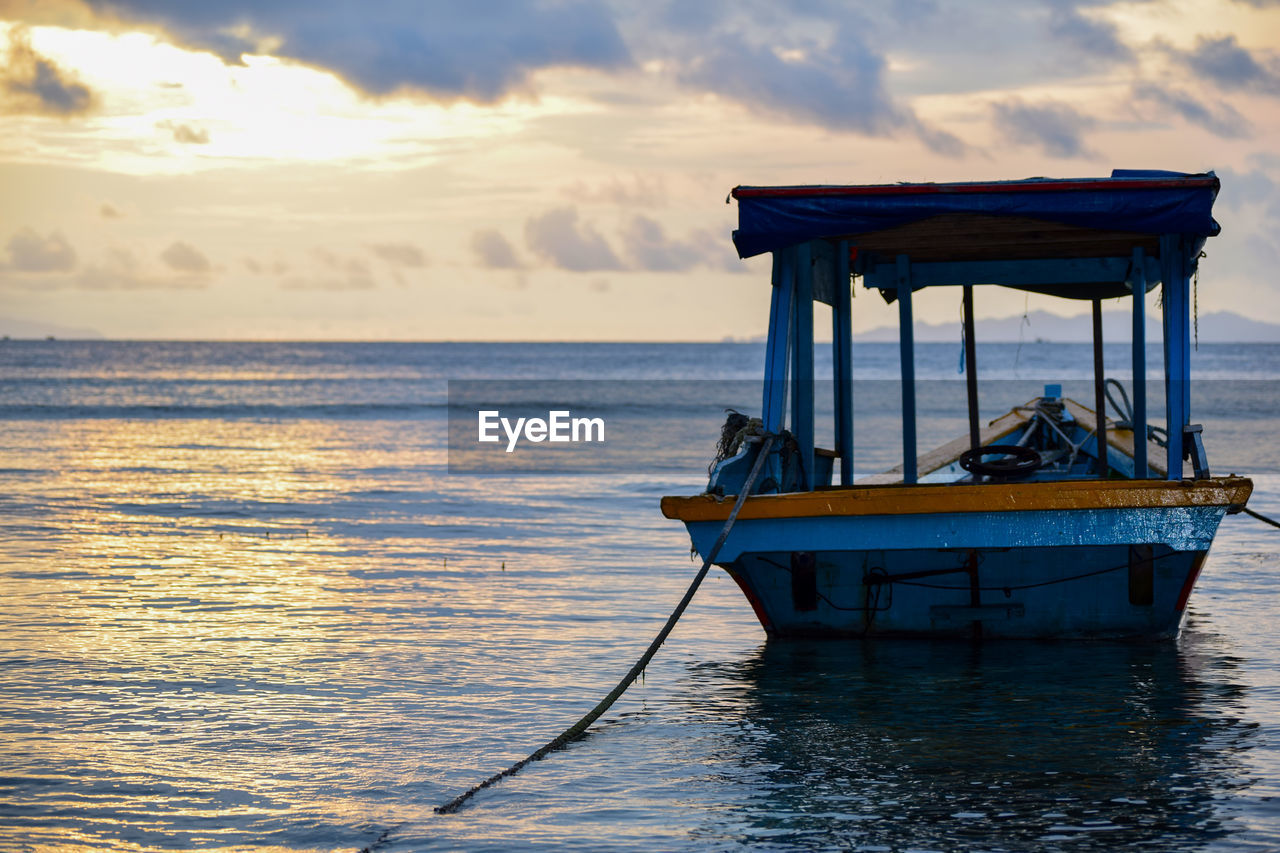 BOAT MOORED IN SEA AGAINST SKY