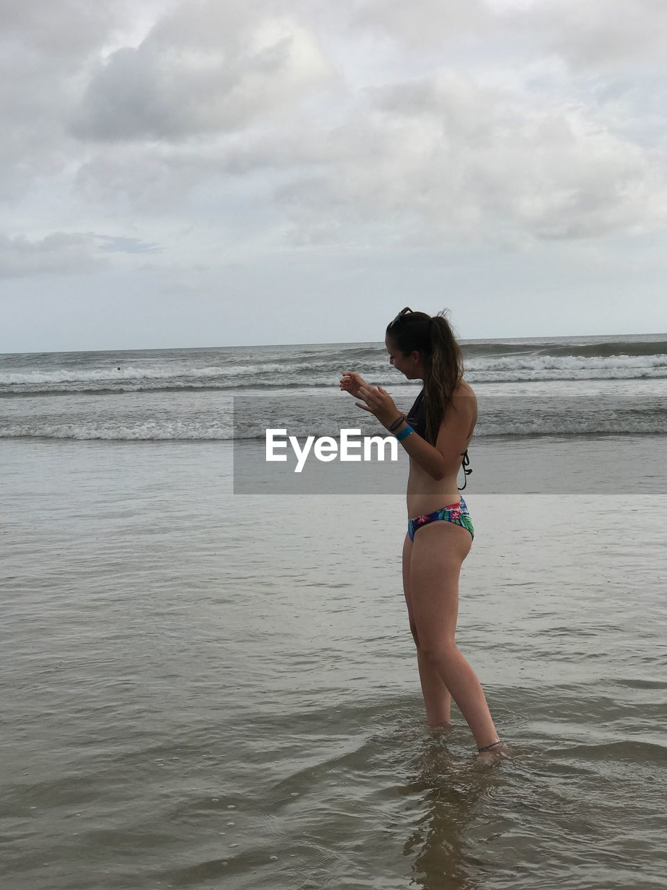 Side view of woman standing on beach against sky