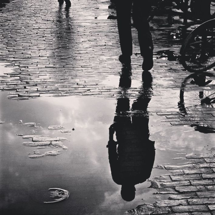REFLECTION OF WOMAN IN PUDDLE