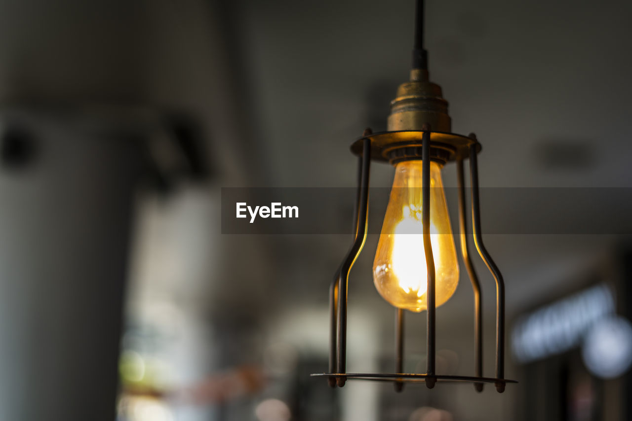 Low angle view of illuminated light bulb hanging from ceiling