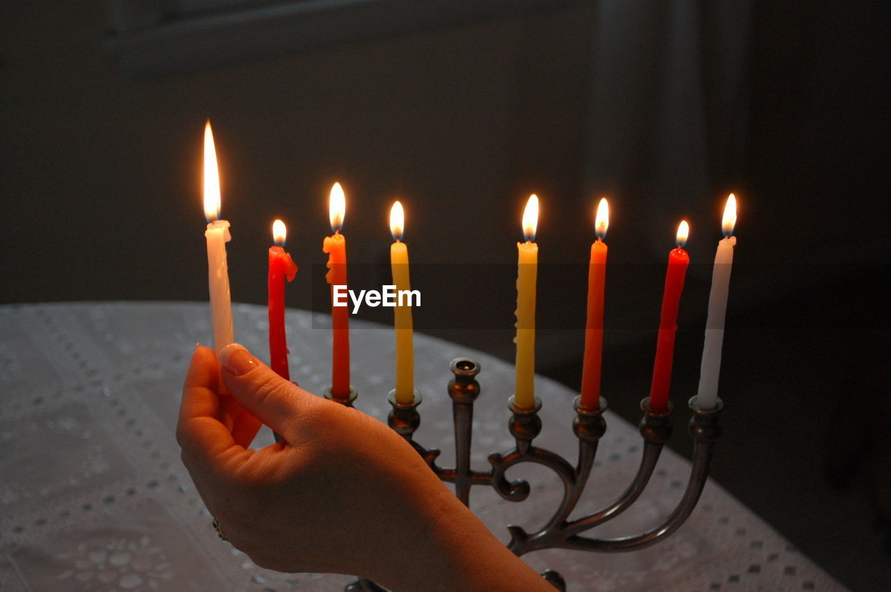 Cropped image of person lighting candles on table