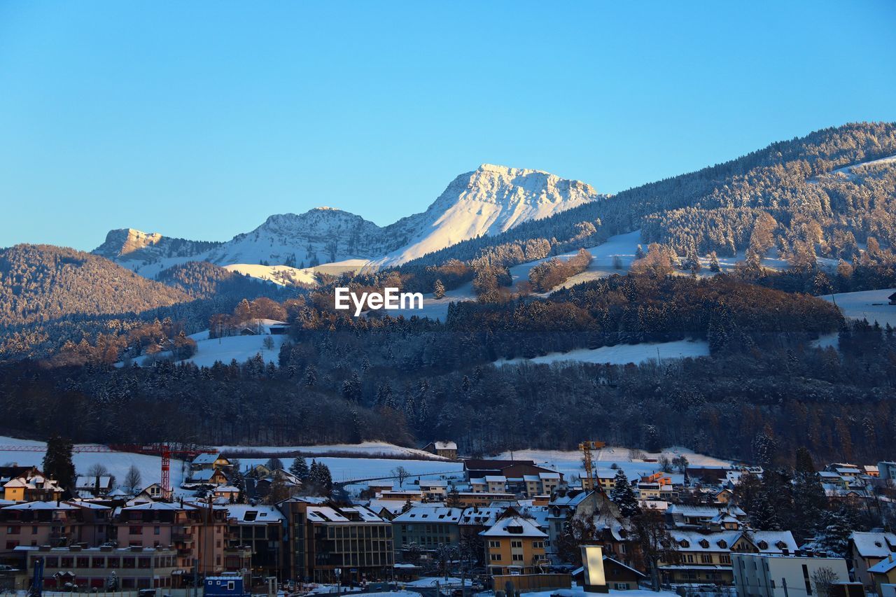View of townscape and mountains against clear blue sky