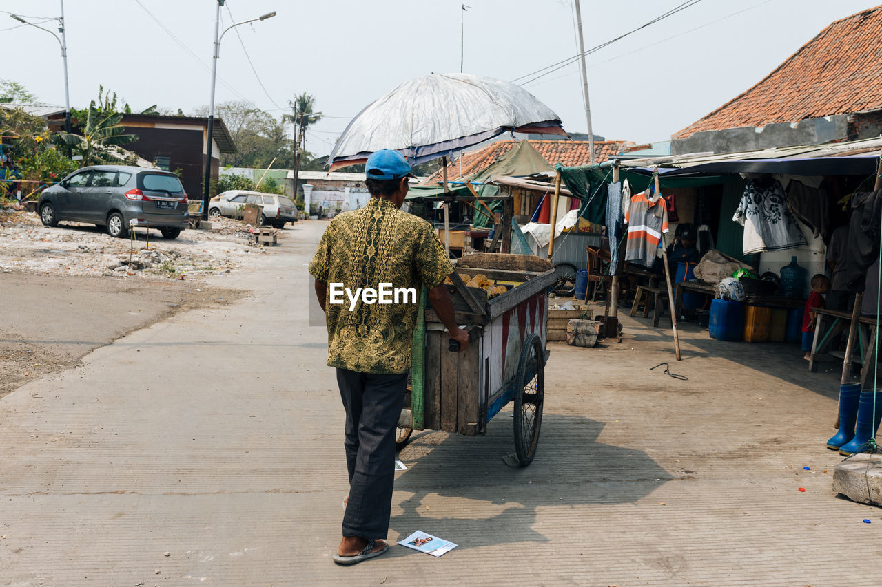 REAR VIEW OF PEOPLE WALKING ON STREET