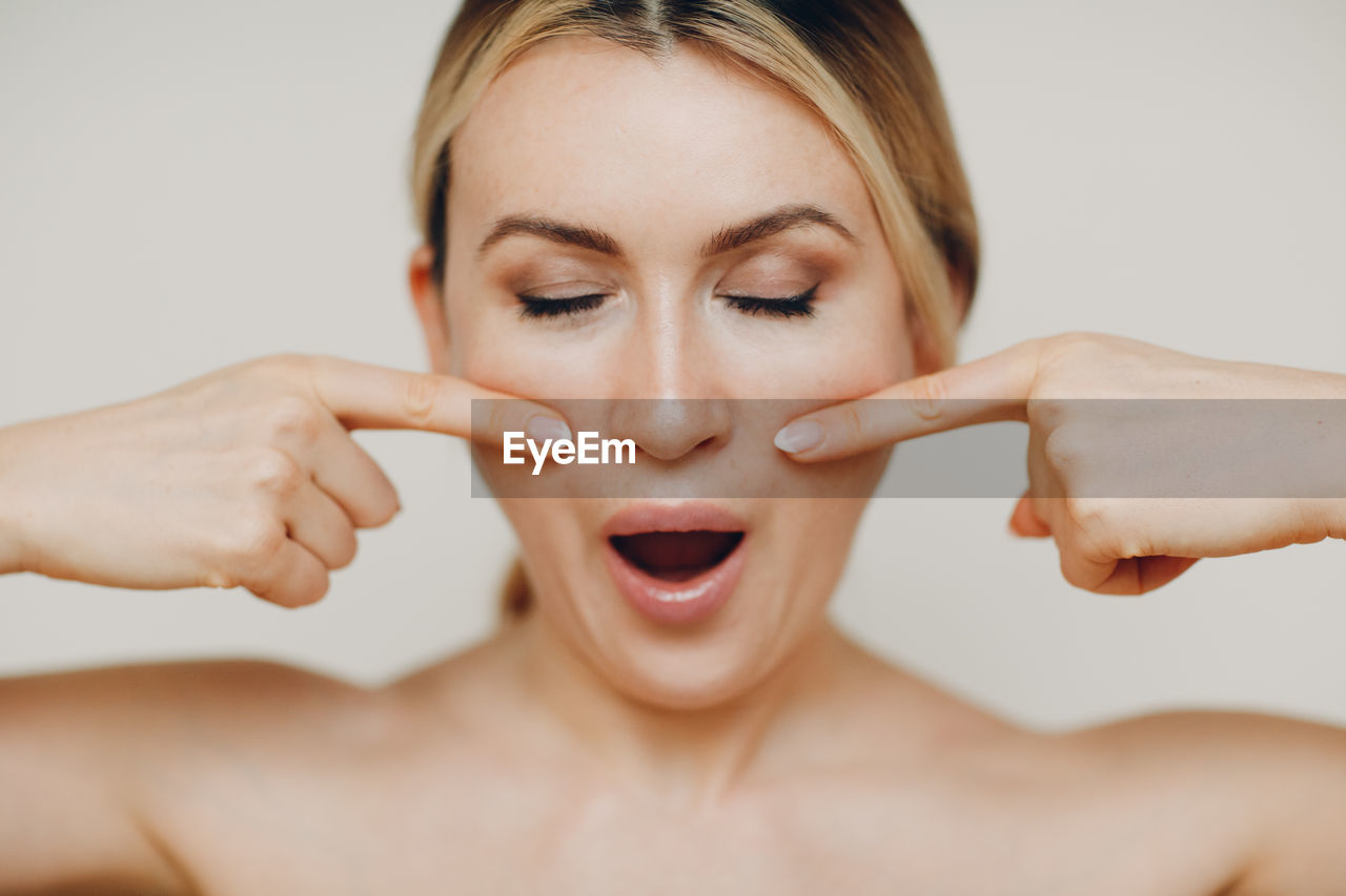 Woman making face against beige background