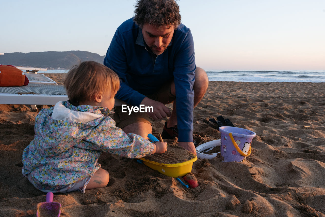 Father and child sitting at the beach in the sunset