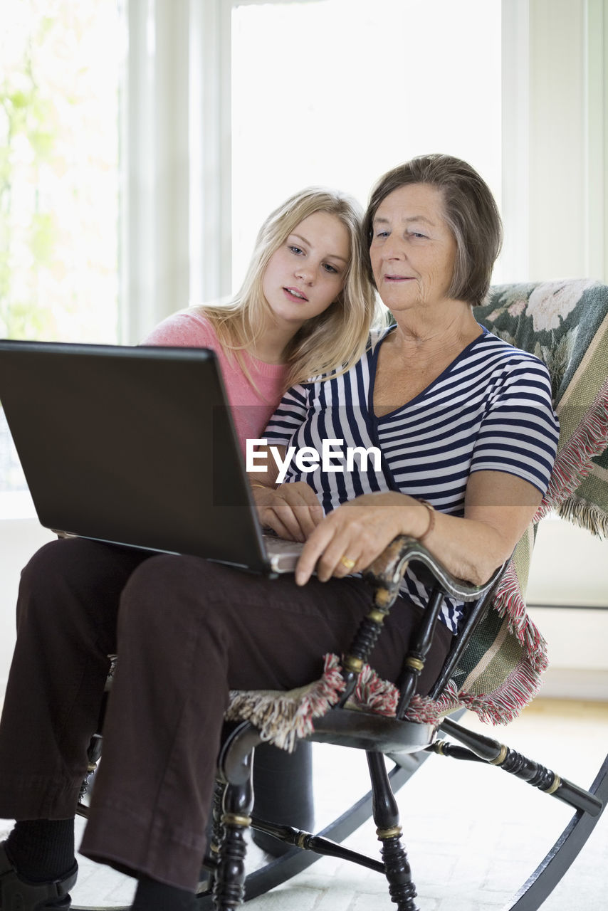 Grandmother and granddaughter using laptop at home