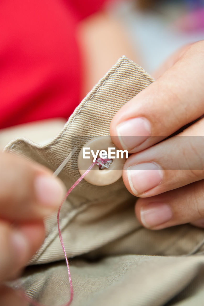 Cropped image of person sewing button