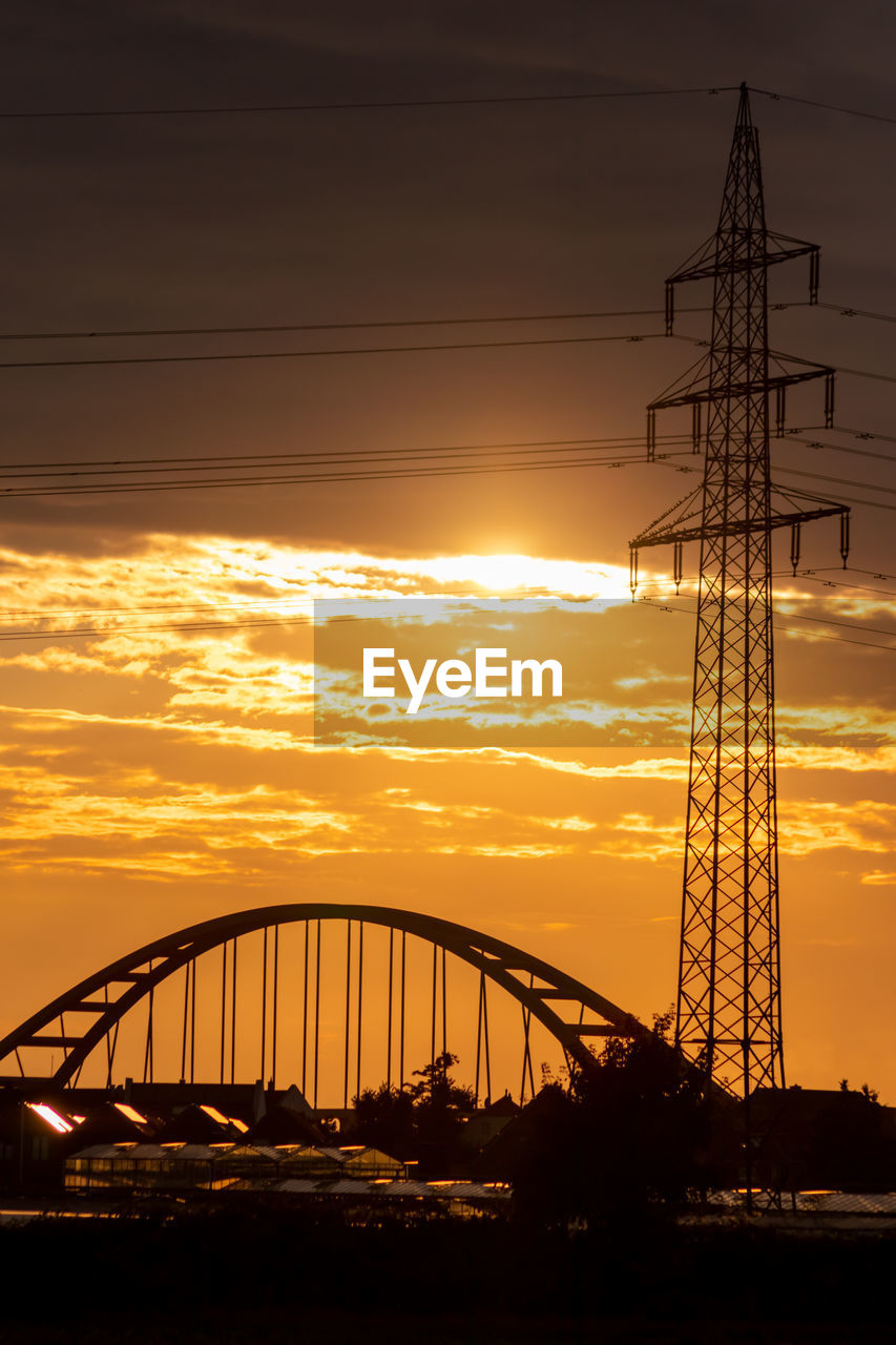 Golden sky with sun rays lens flare show solar energy electricity tower pylon silhouette sunset