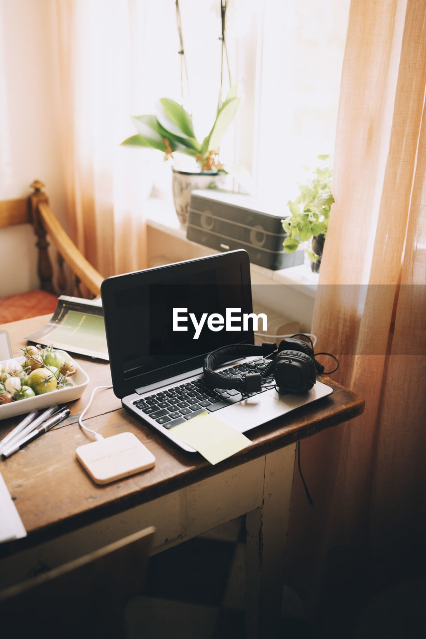 High angle view of laptop with headphones by window on table at home