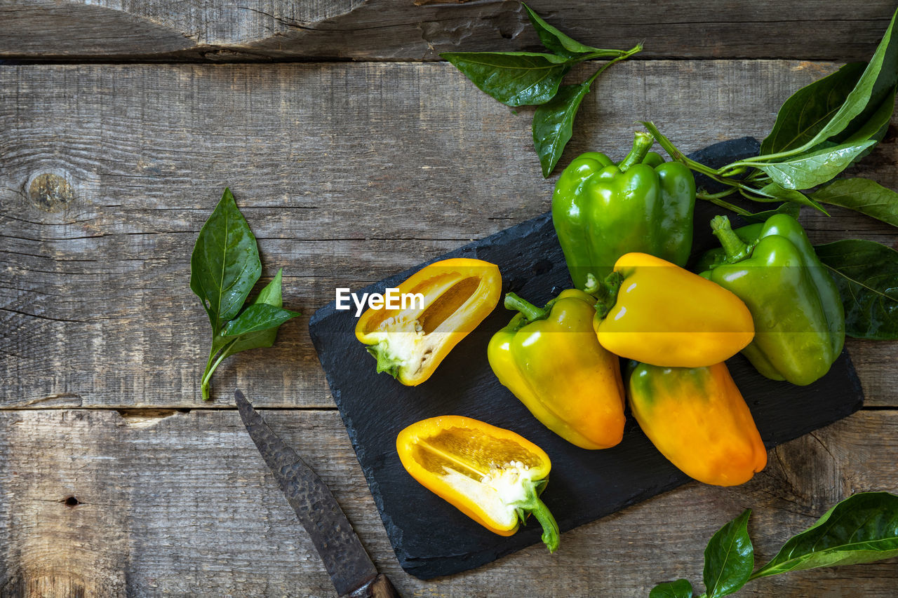 Organic healthy raw ripe sweet pepper, yellow paprika, on a kitchen wooden table. 