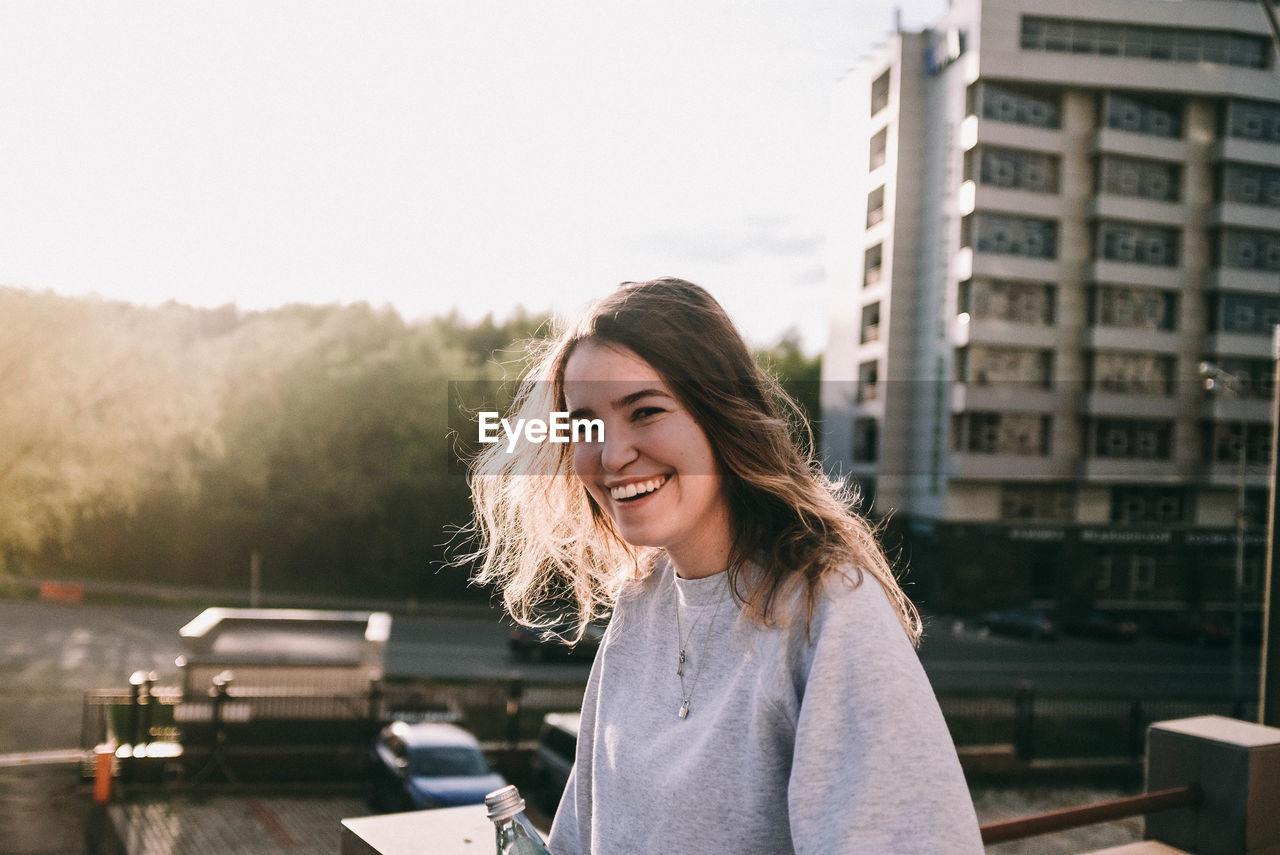 Portrait of smiling woman standing against trees