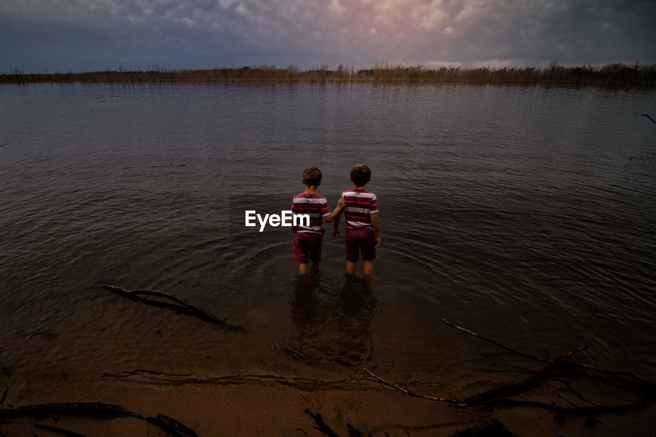 Rear view of men in lake against sky