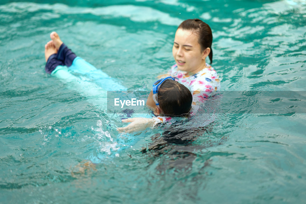 Mom hold kid practice swimming in pool