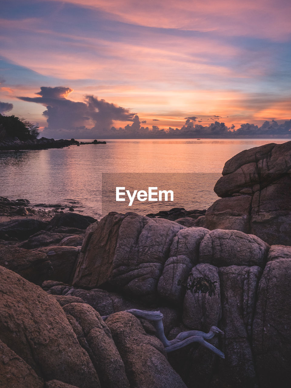 Scenic view of sea against orange sky during sunrise with textured rocky beach. koh samui, thailand.