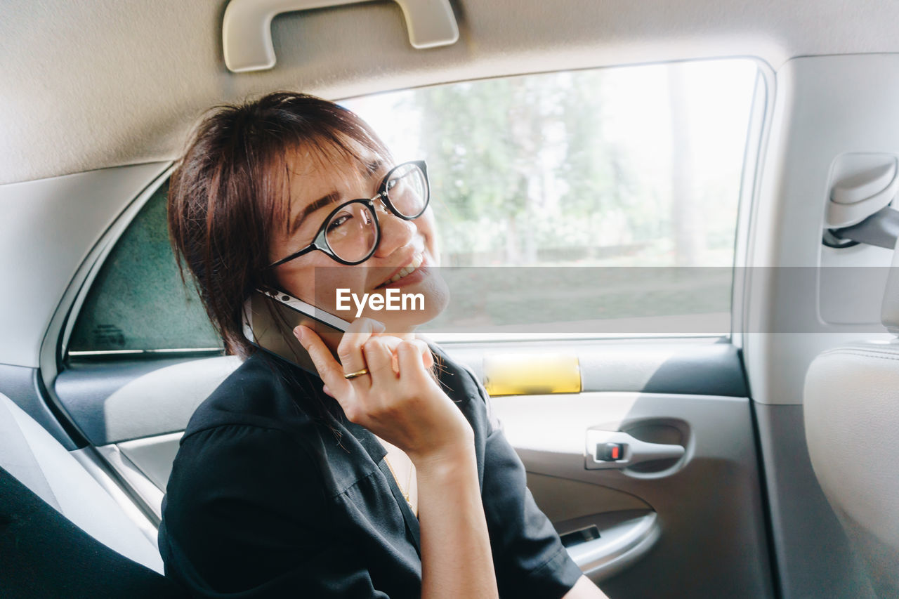 PORTRAIT OF WOMAN USING PHONE IN CAR