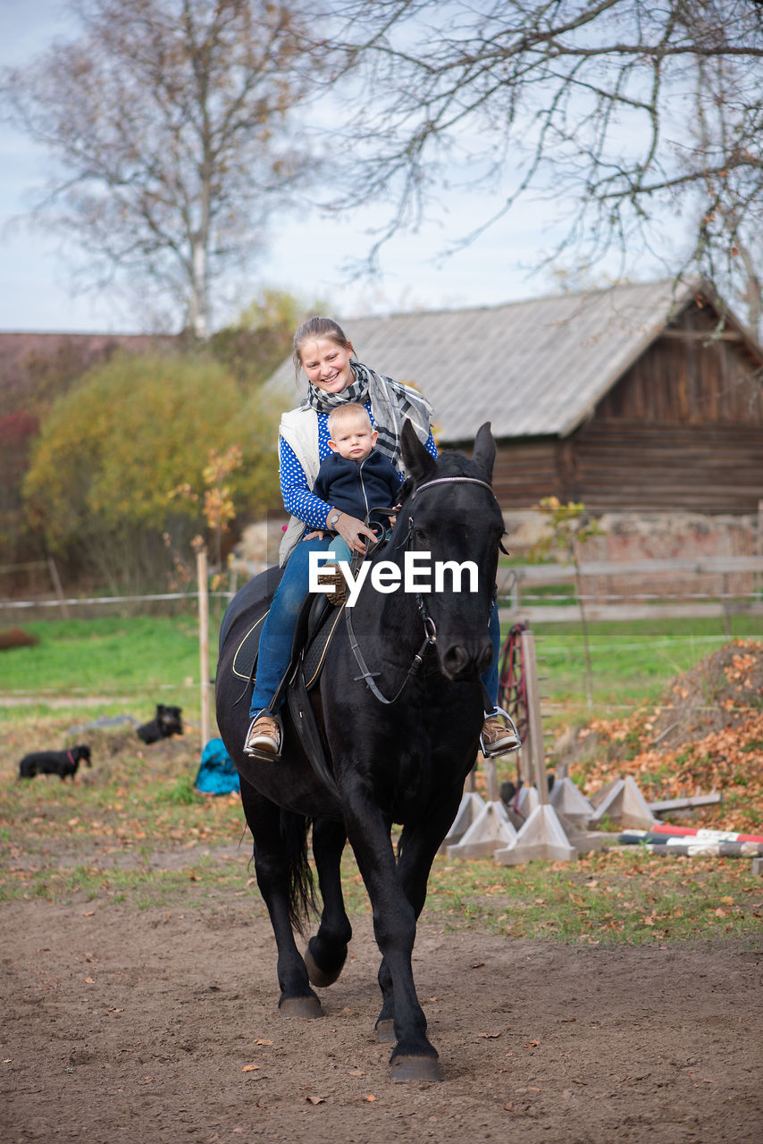 Woman sitting with baby boy on horse at field