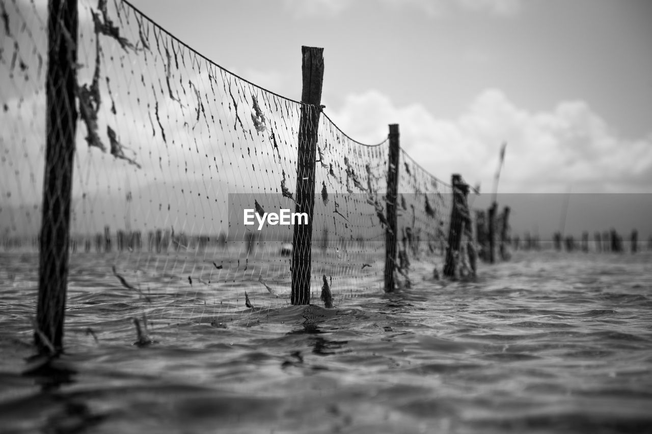 Close-up of fishing net in sea against sky