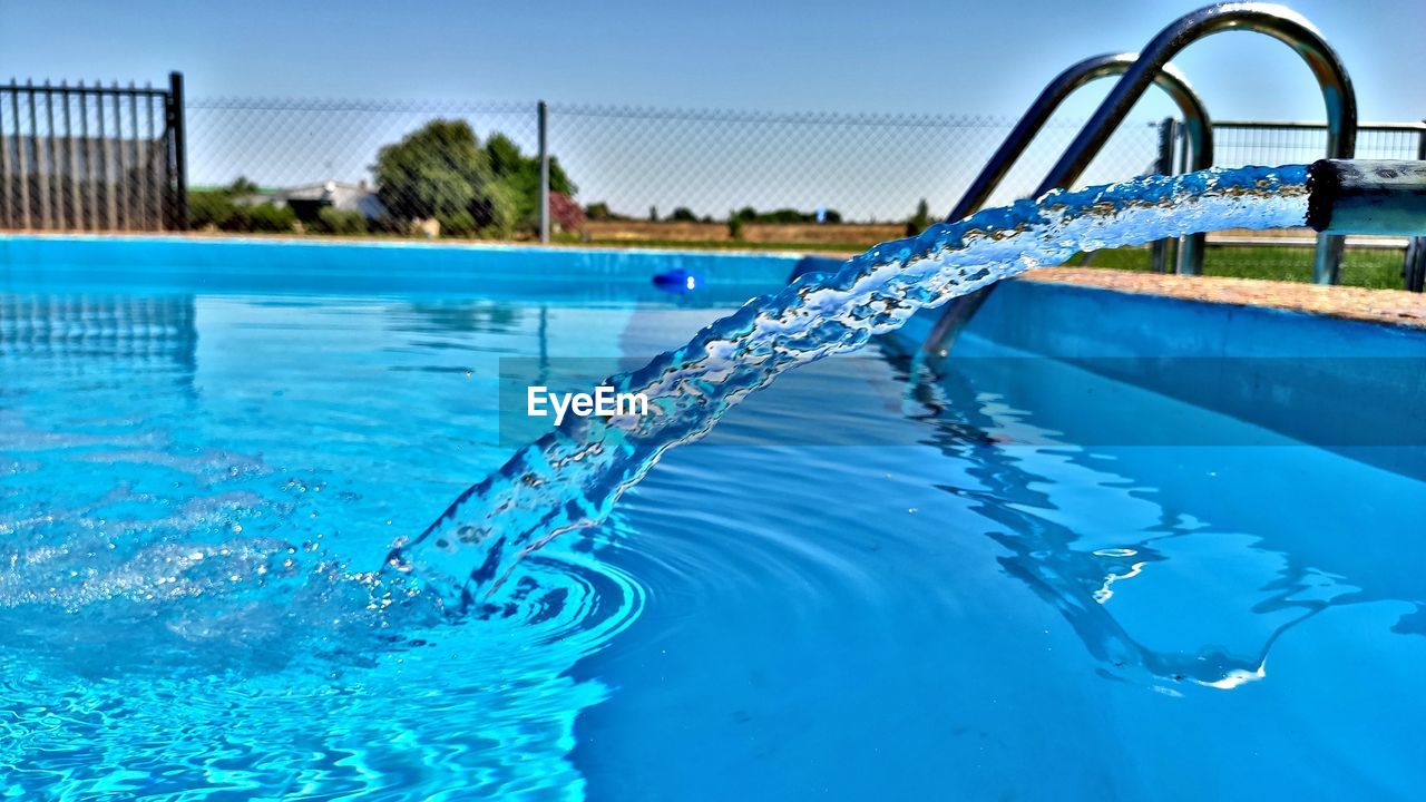 Water splashing in swimming pool against blue sky